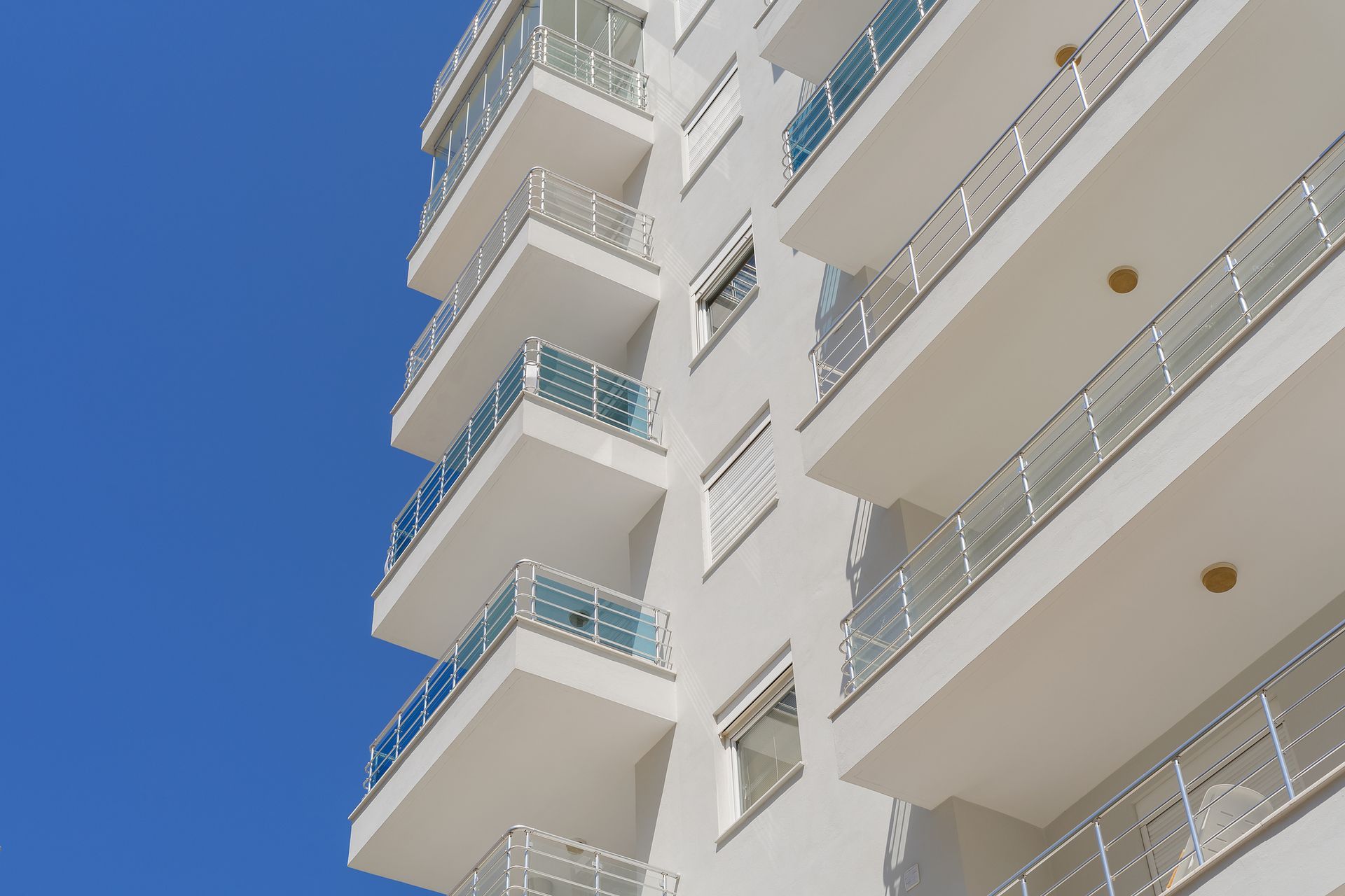 Un alto edificio bianco con balconi e un cielo azzurro sullo sfondo.