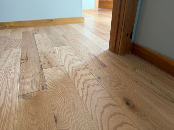 Un primo piano di un pavimento in legno con una porta sullo sfondo.
