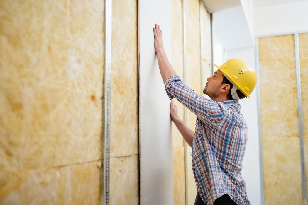 Un uomo sta installando l'isolamento su un muro.