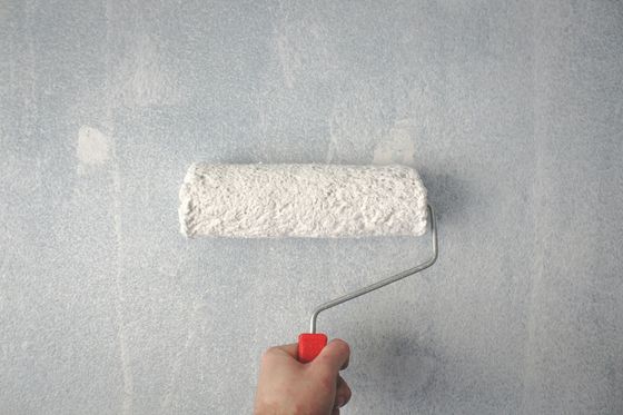 Una persona sta dipingendo un muro con un rullo.