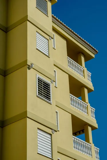 Un edificio giallo con balconi e persiane alle finestre