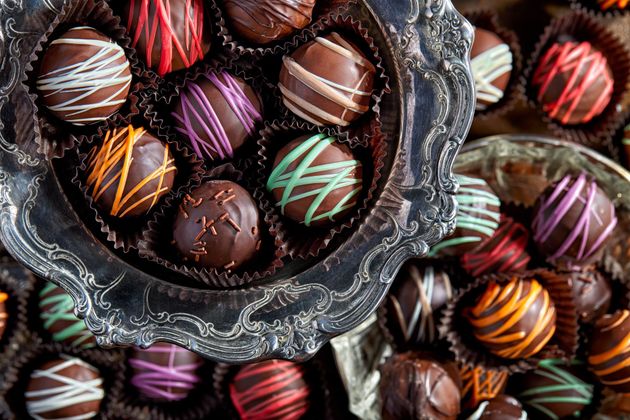 Chocolate truffles in silver dish, decorated with colorful drizzle.