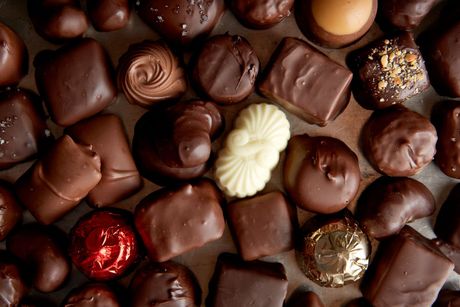 Assorted chocolates in various shapes and colors, some with nuts, a single white chocolate.