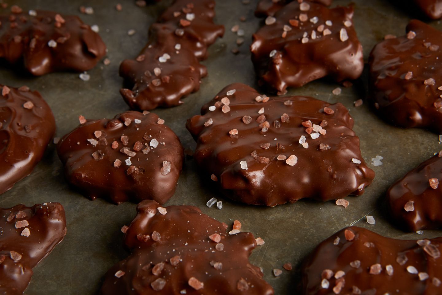 Chocolate-covered pretzels, sprinkled with coarse salt, on parchment paper.