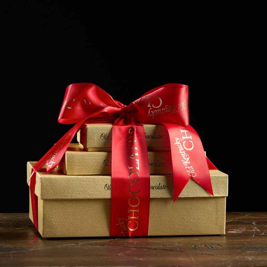 Gift boxes stacked with a red bow on a wooden surface.