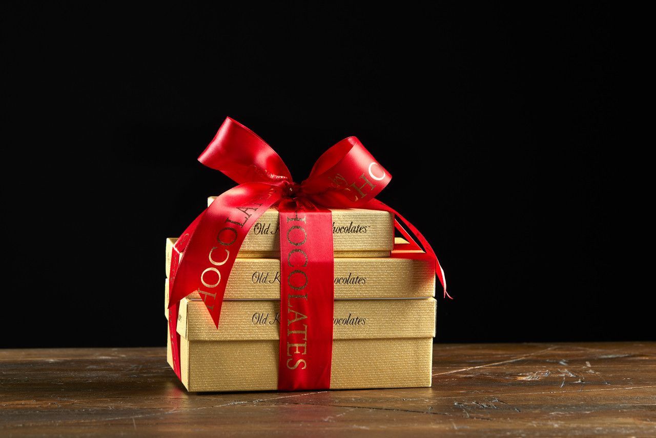 Stack of gold gift boxes with a red ribbon tied in a bow.
