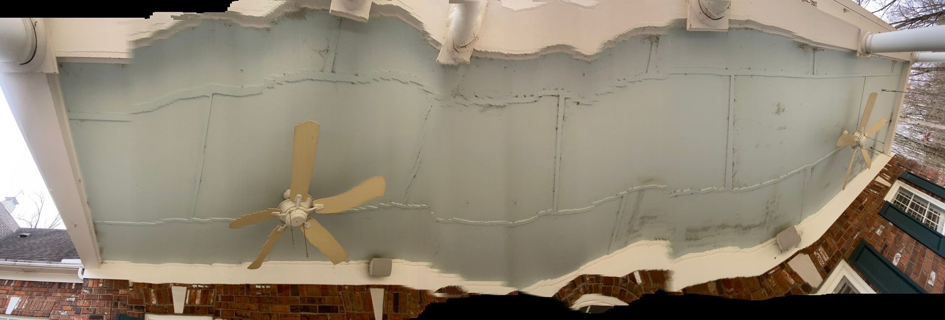 Cracked ceiling with a ceiling fan. The surface is light blue-gray, showing damage and wear.
