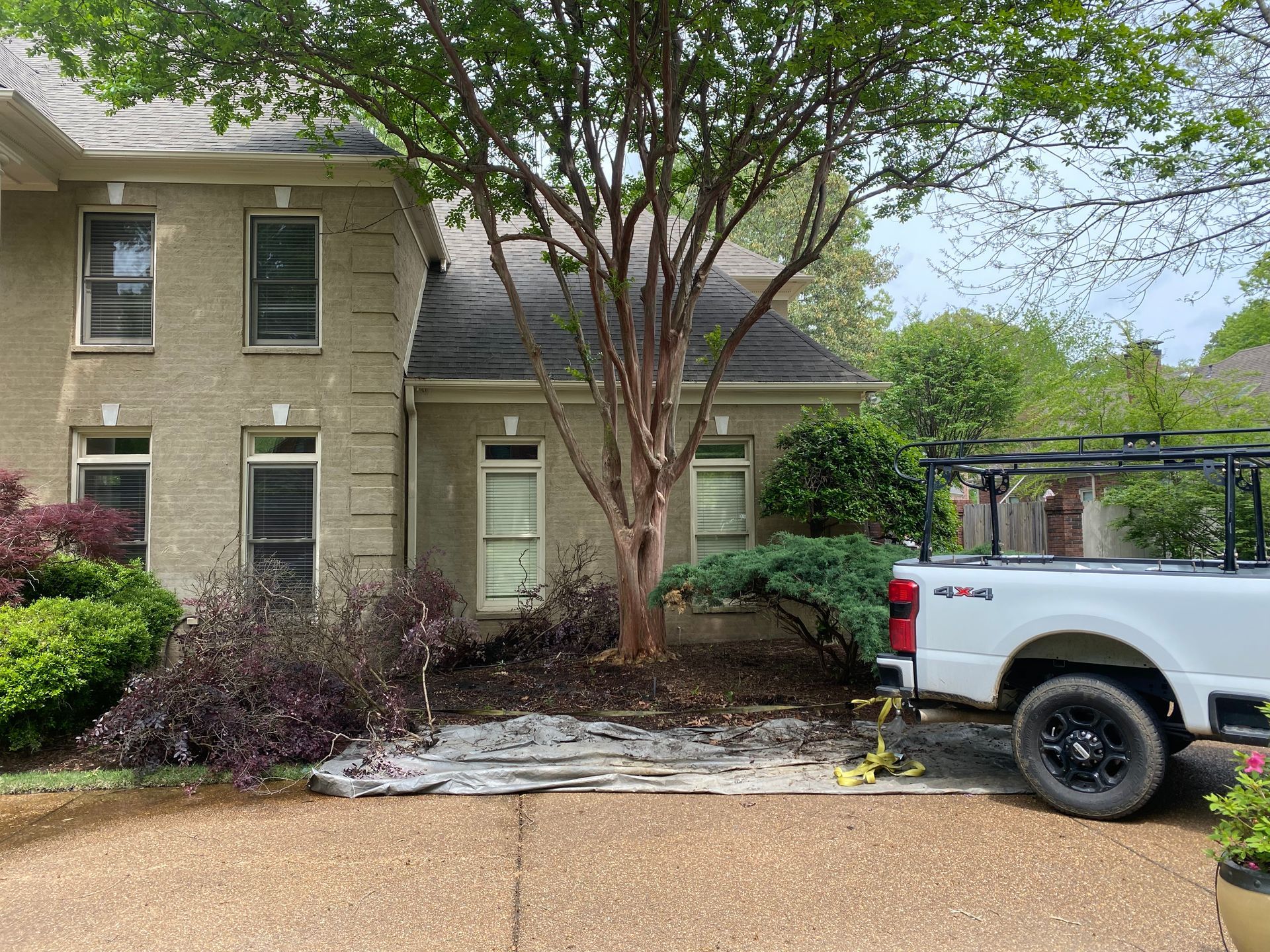 A white truck parked next to a house with a tree in front. The house is beige brick.