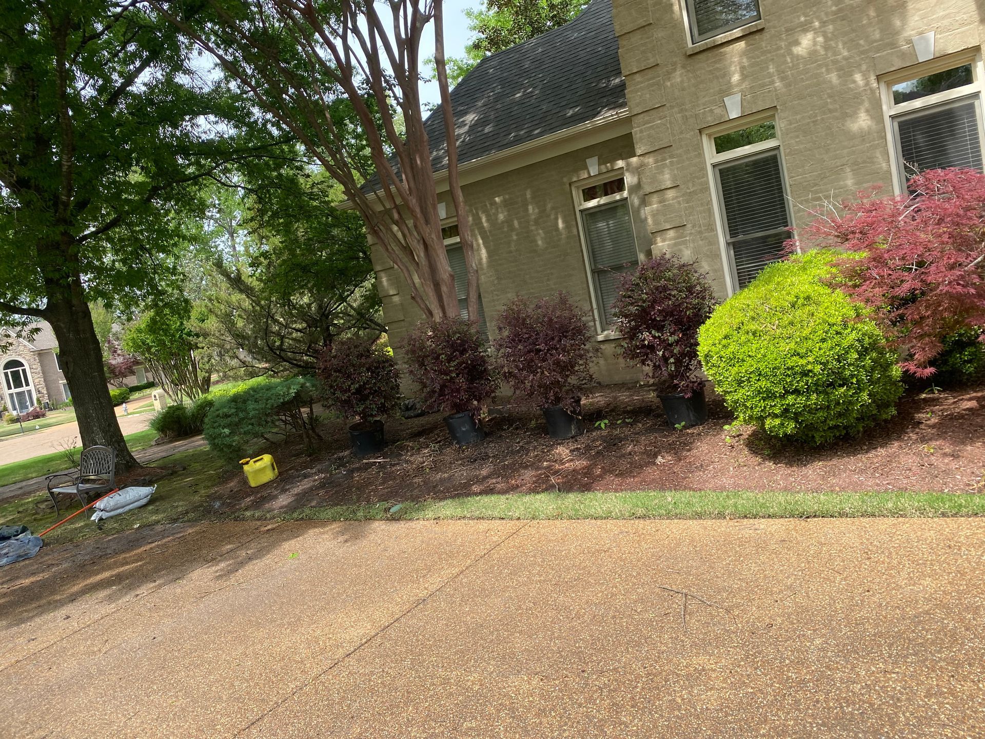 House with landscaping featuring red and green bushes, a brown gravel driveway, and a green lawn.