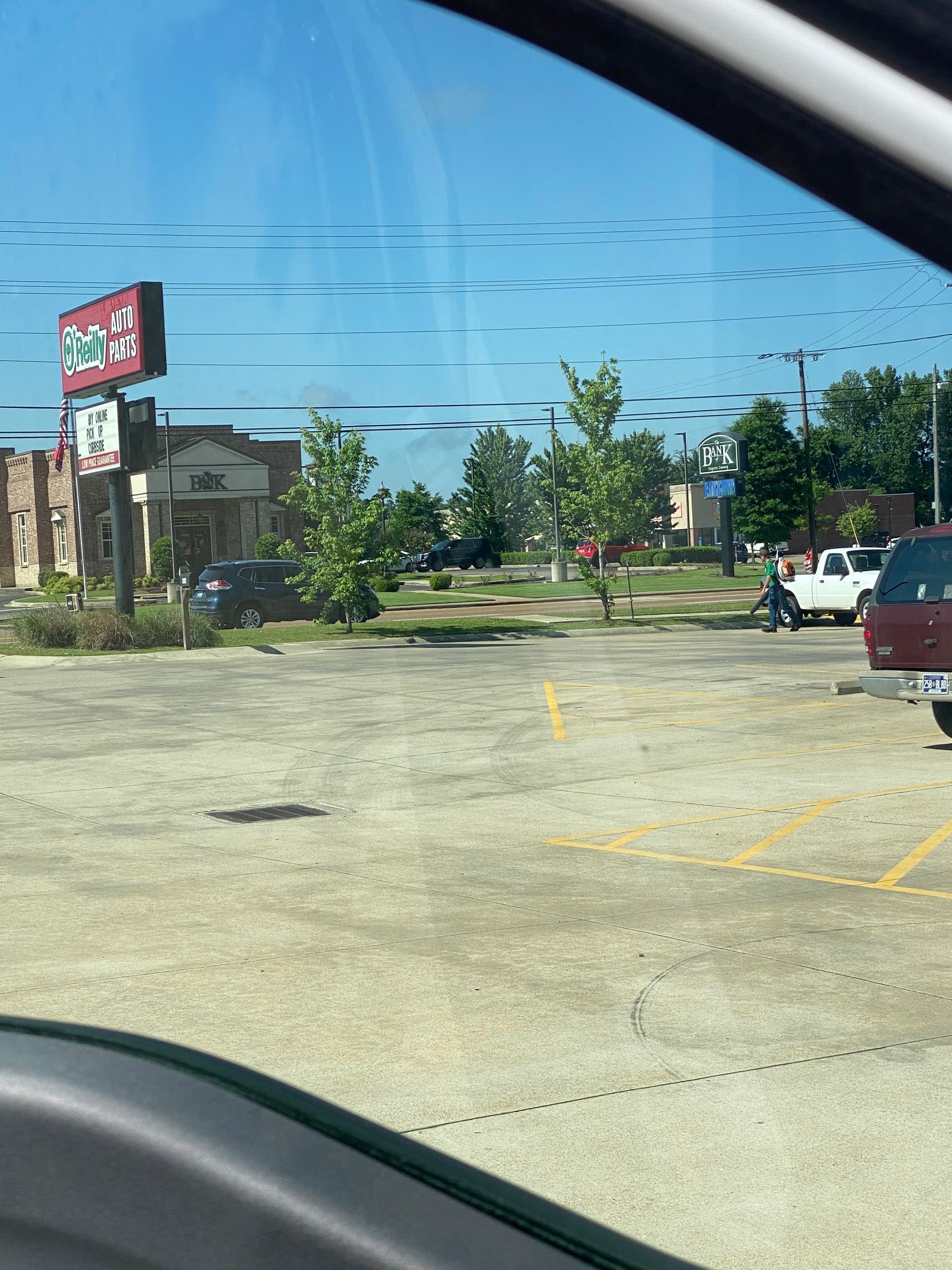View of a parking lot with several cars. A restaurant sign is visible with a blue sky in the background.