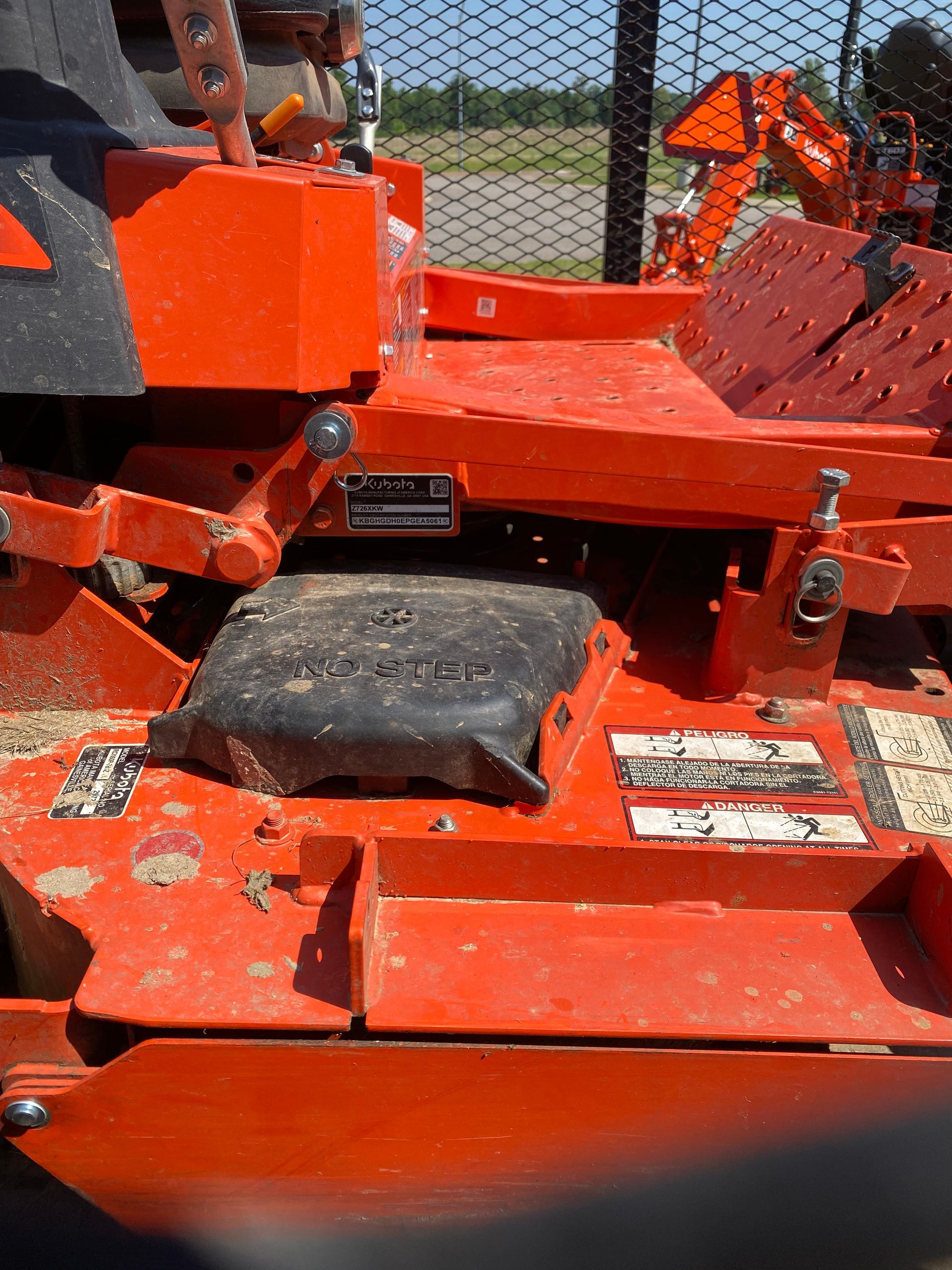 Close-up of a bright orange commercial lawnmower, showing the seat, control panel, and cutting deck.