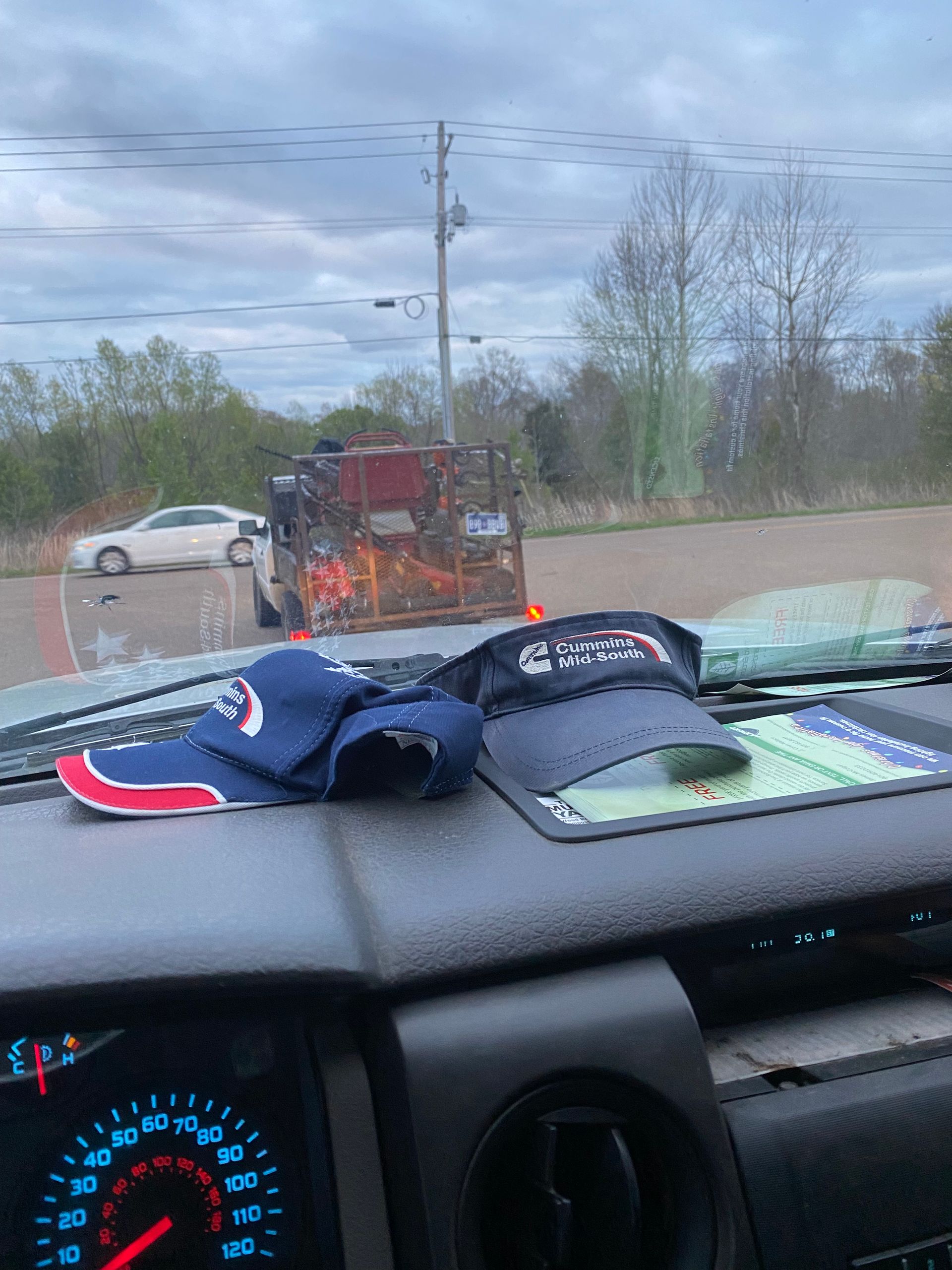 Dashboard with two hats. In the background is a burning trailer on the road.