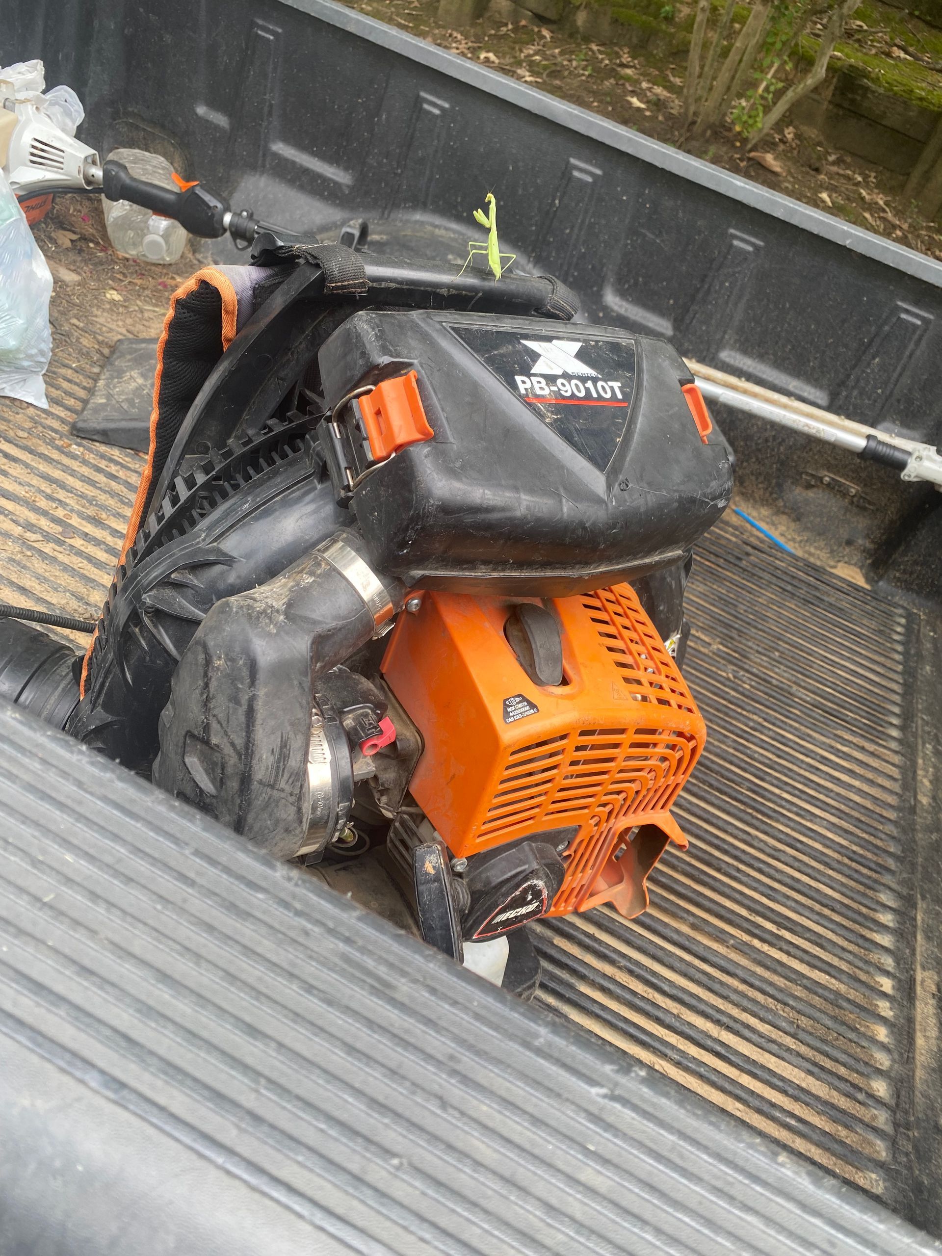 An orange and black engine in the bed of a truck, presumably for landscaping or construction.