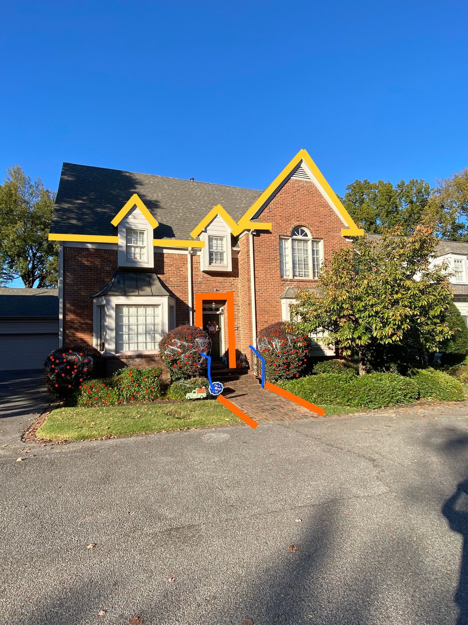 A two-story brick building with a blue ramp leading to the front door. The door and surrounding trim are orange, and the sky is clear blue.