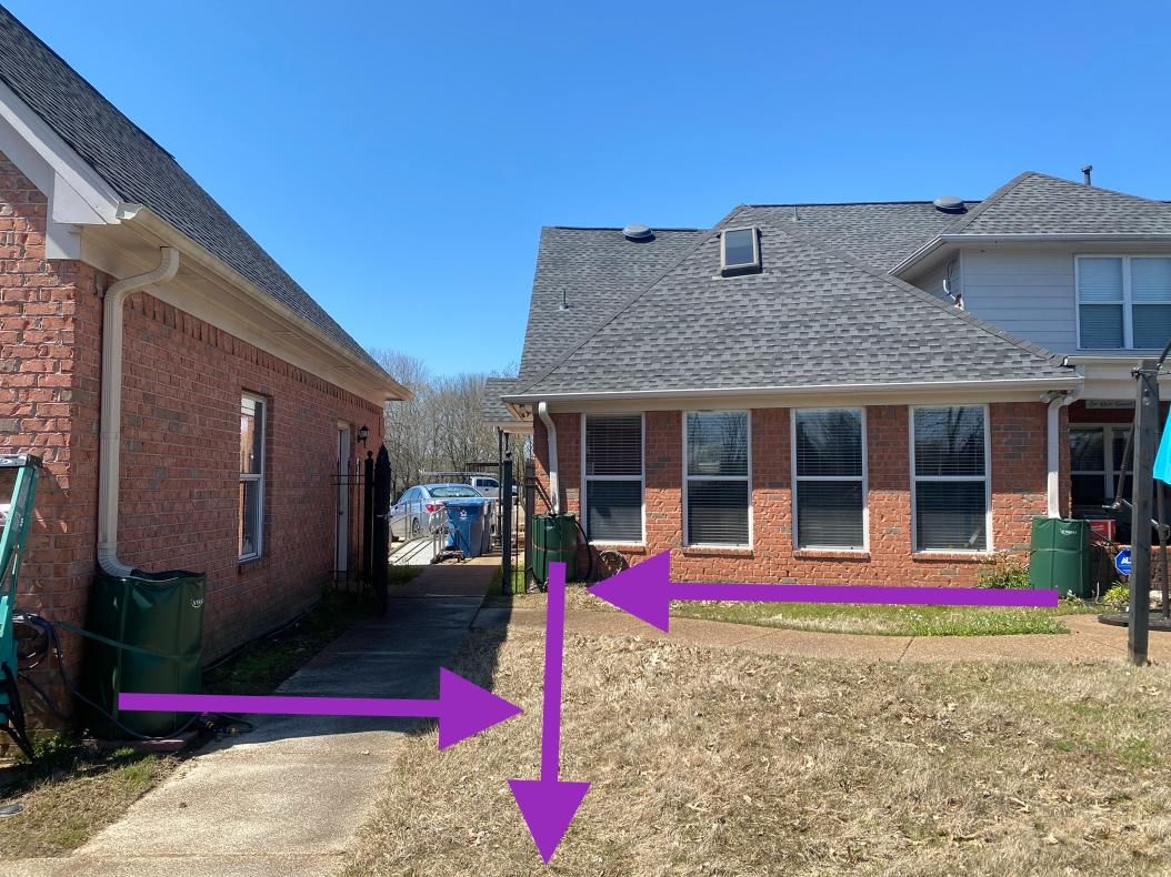 A brick building and house with a narrow walkway in between, indicated by purple arrows.