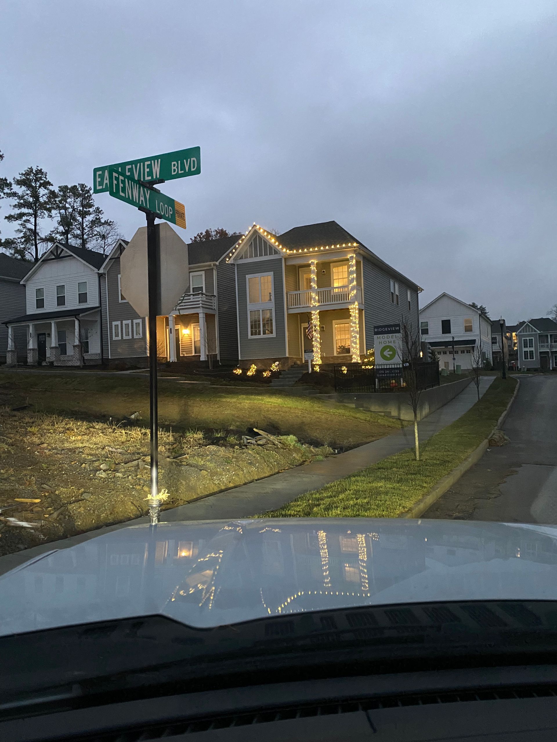 Street corner view of houses, with the street name signs “Easton Wood” and “Parkway”. Some houses have lights.