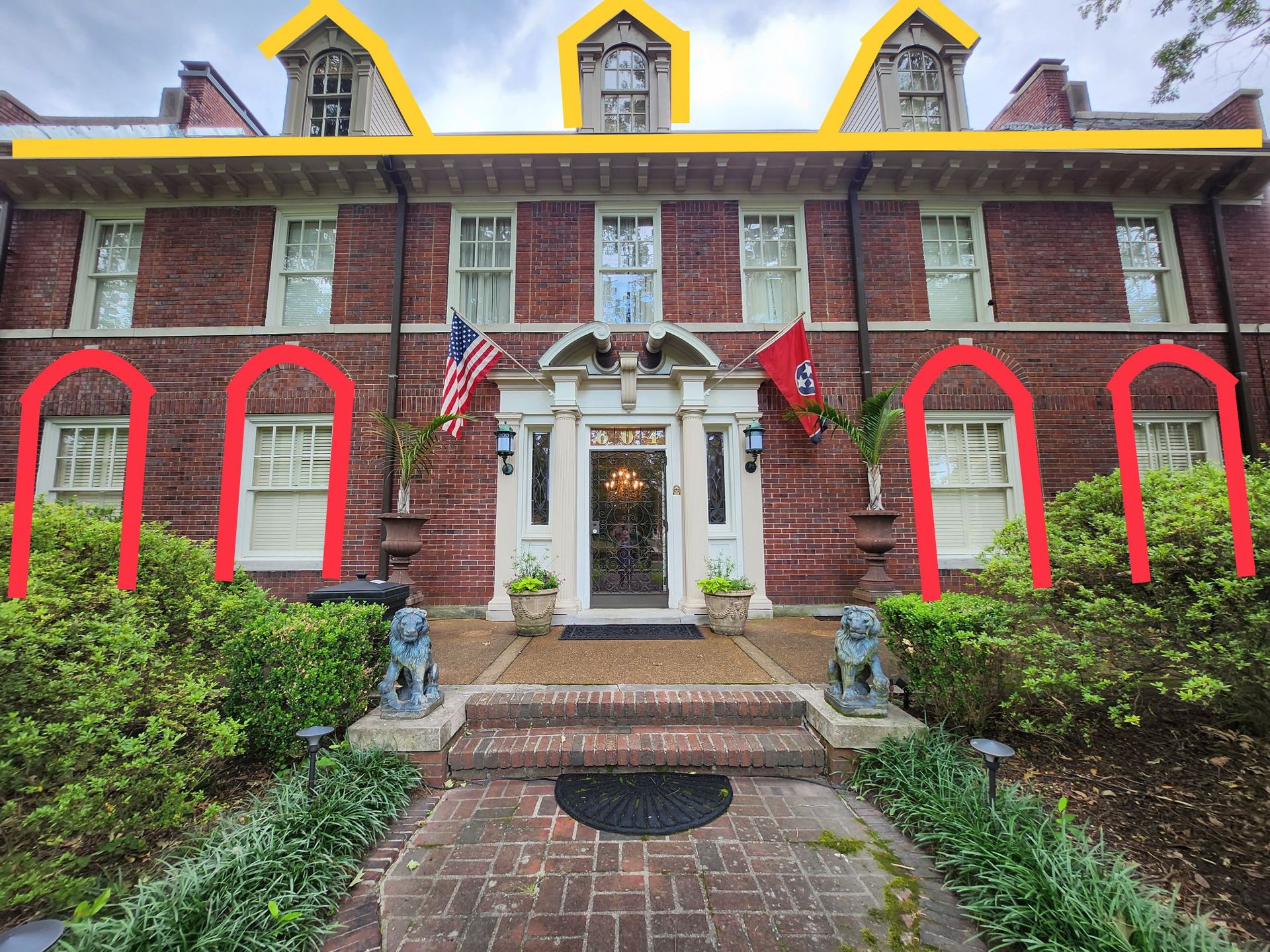 Red brick mansion with arched windows, three dormers, and a central doorway with an American flag and Tennessee flag.