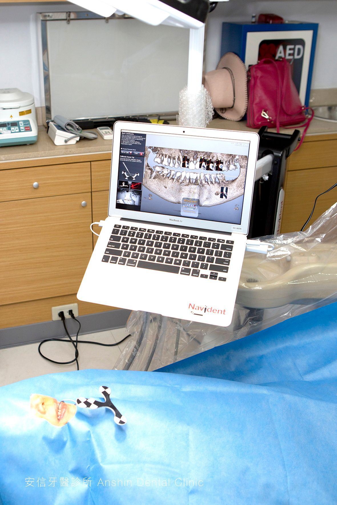 A laptop is sitting on a dental chair in front of a sign that says aed