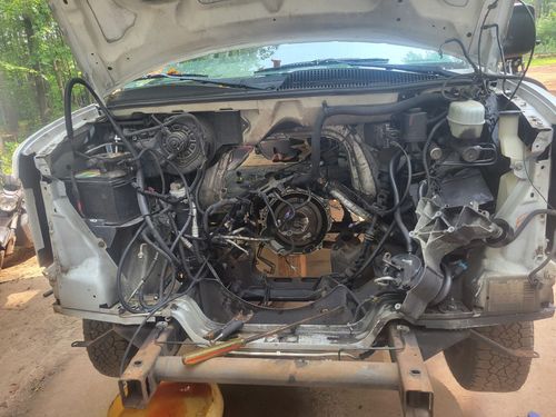 A white truck with the hood up is being worked on.