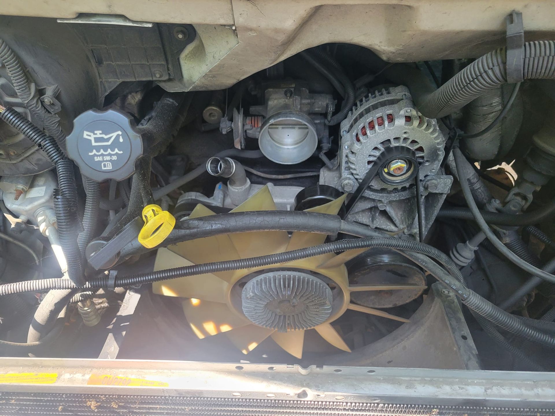 A close up of the engine of a car with the hood open.