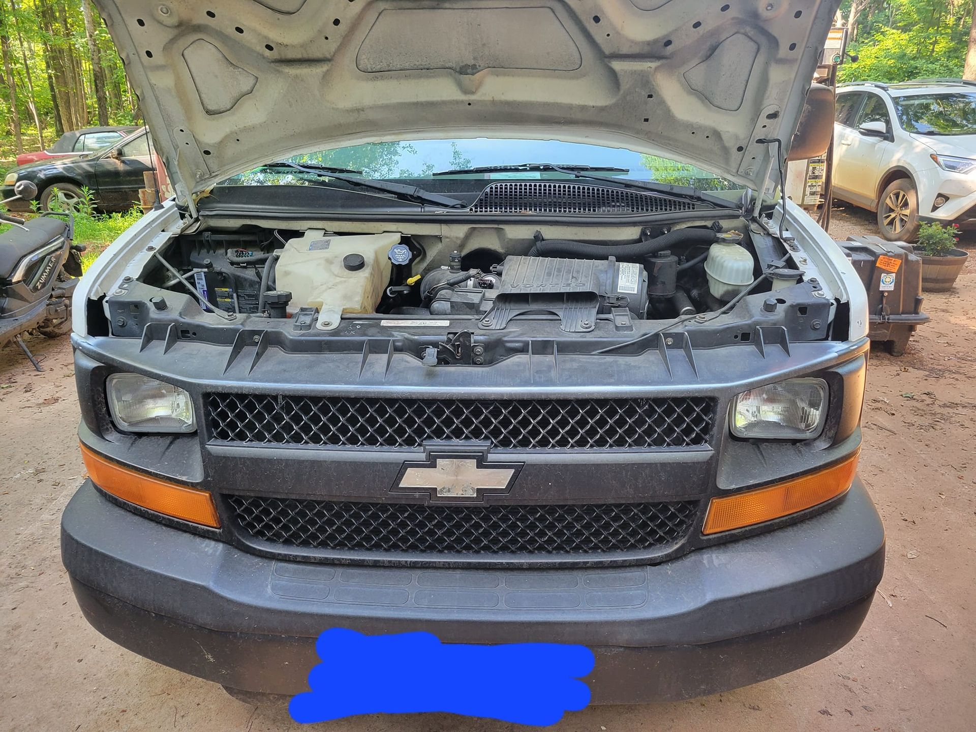The hood of a chevrolet van is open and the engine is visible.