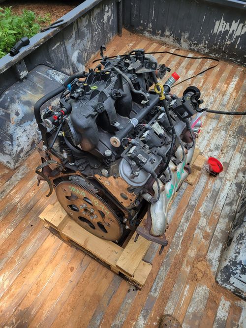 The engine is sitting on a wooden pallet in the back of a truck.