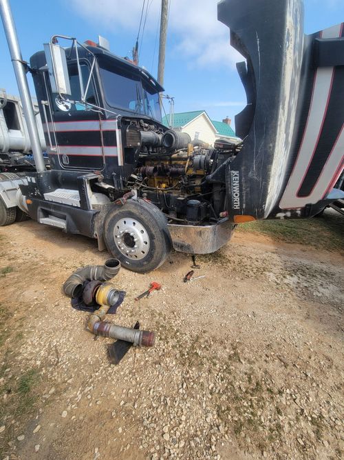 A semi truck is being repaired on the side of the road.