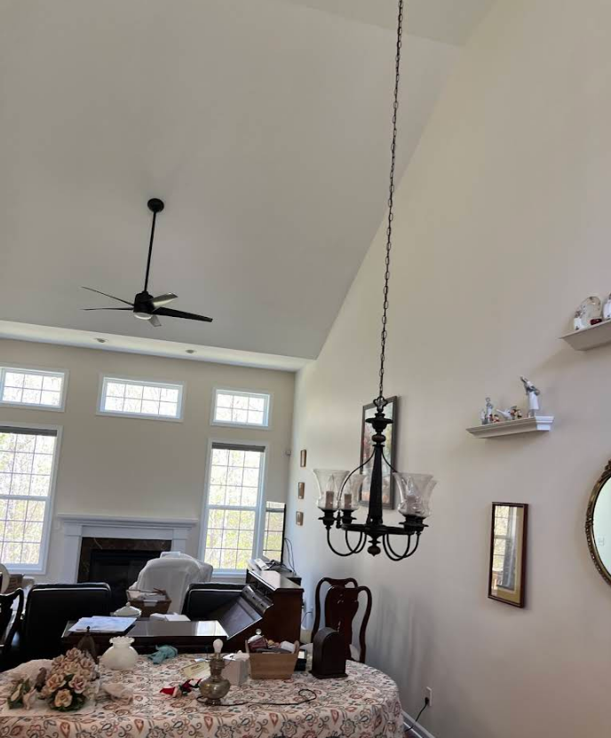 A living room with a ceiling fan and a chandelier hanging from the ceiling.