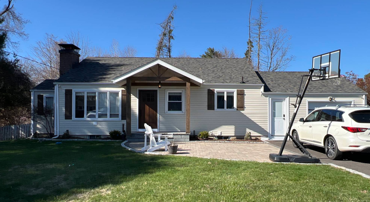 A white house with a basketball hoop in front of it.