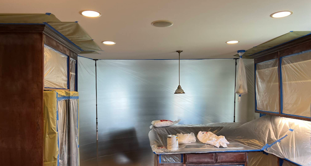 A kitchen is being painted and covered in plastic.