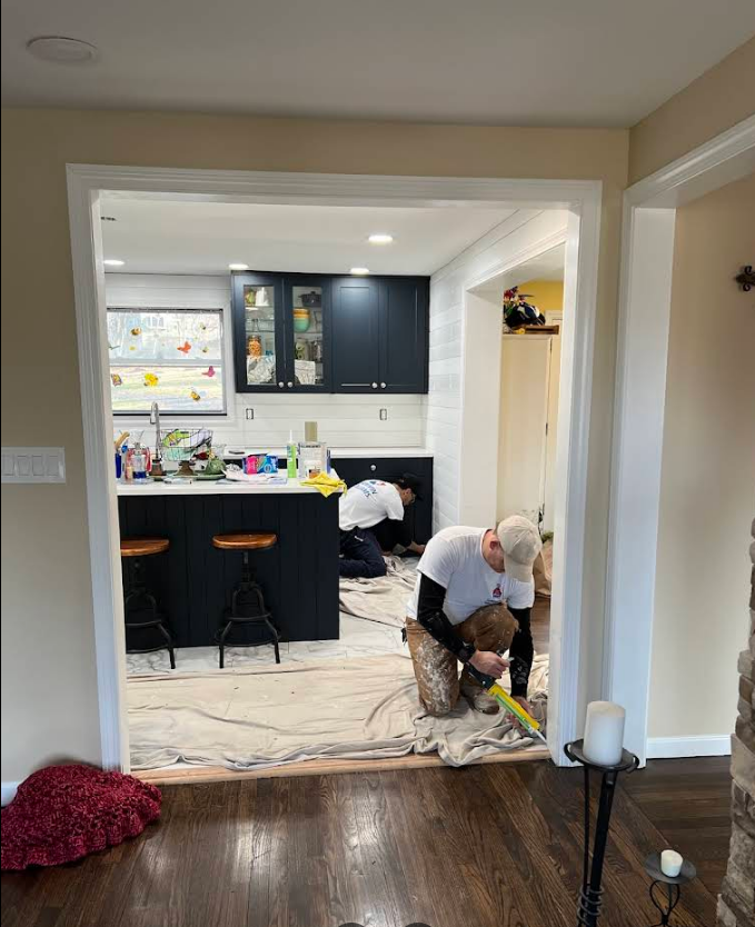A man is measuring a piece of wood in a kitchen.