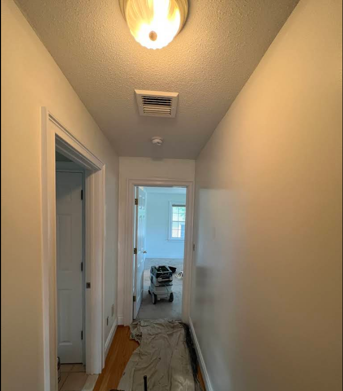 A hallway with white walls and a light on the ceiling