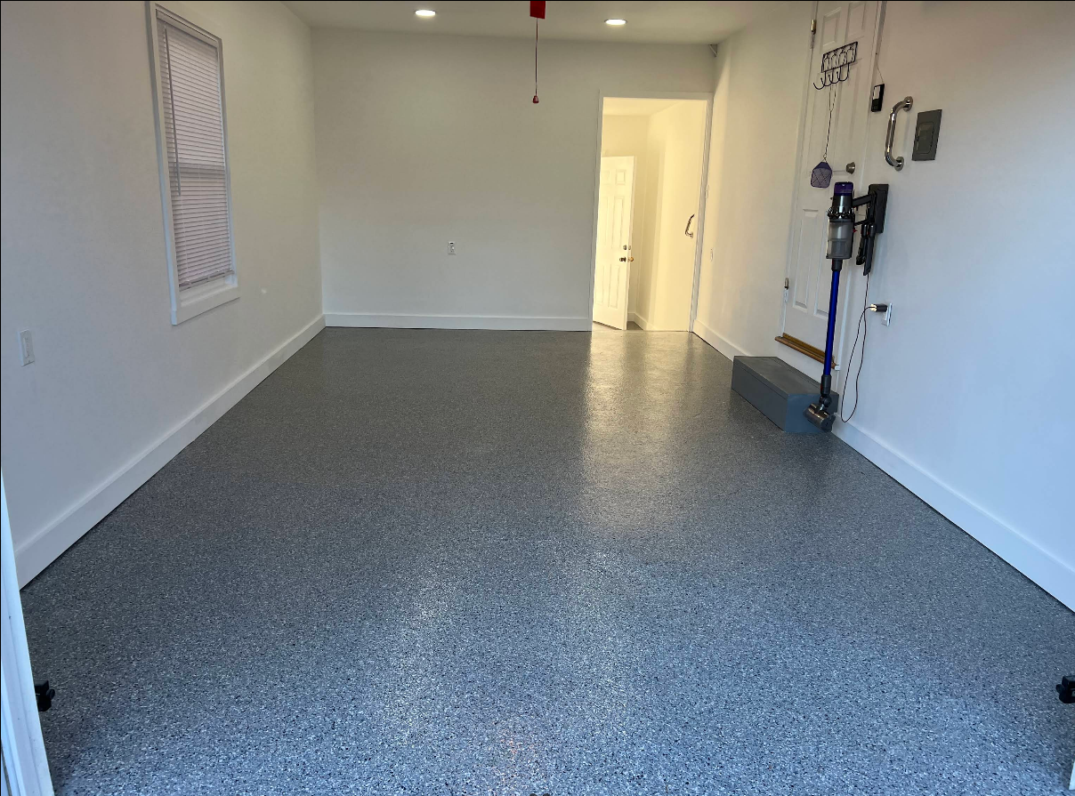 An empty garage with a gray floor and white walls.