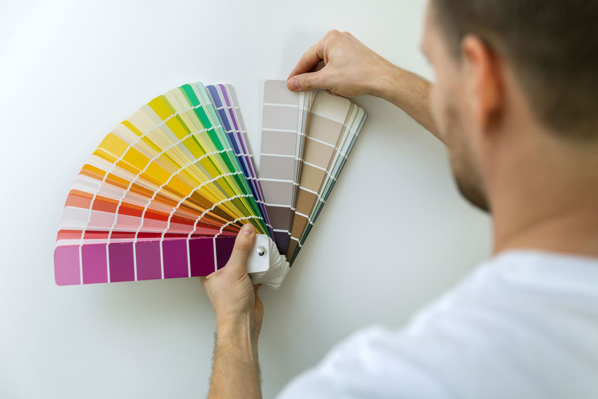 A man is holding a fan of paint samples in his hands.