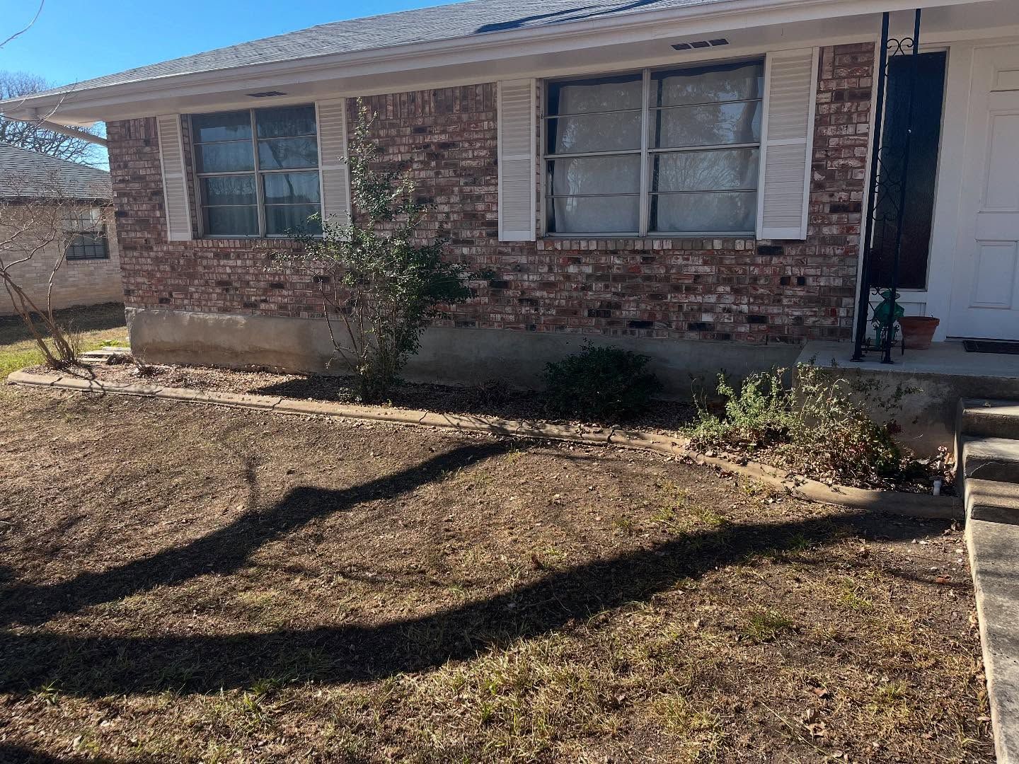 Brick house with shutters, small yard, and long shadow.