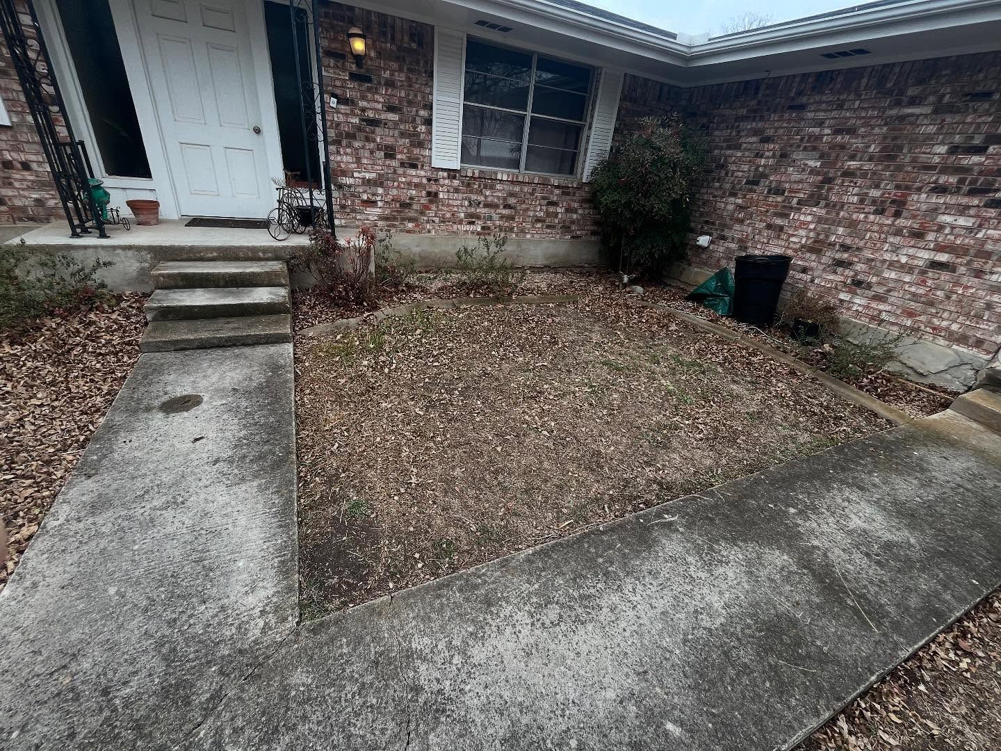 Exterior of a brick home with a concrete walkway leading to the front door. The yard is covered in brown leaves.