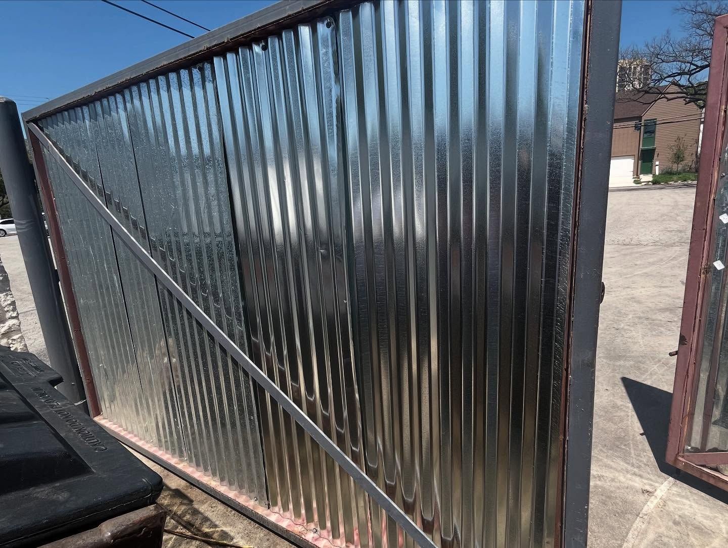 Galvanized metal gate with vertical ridges.