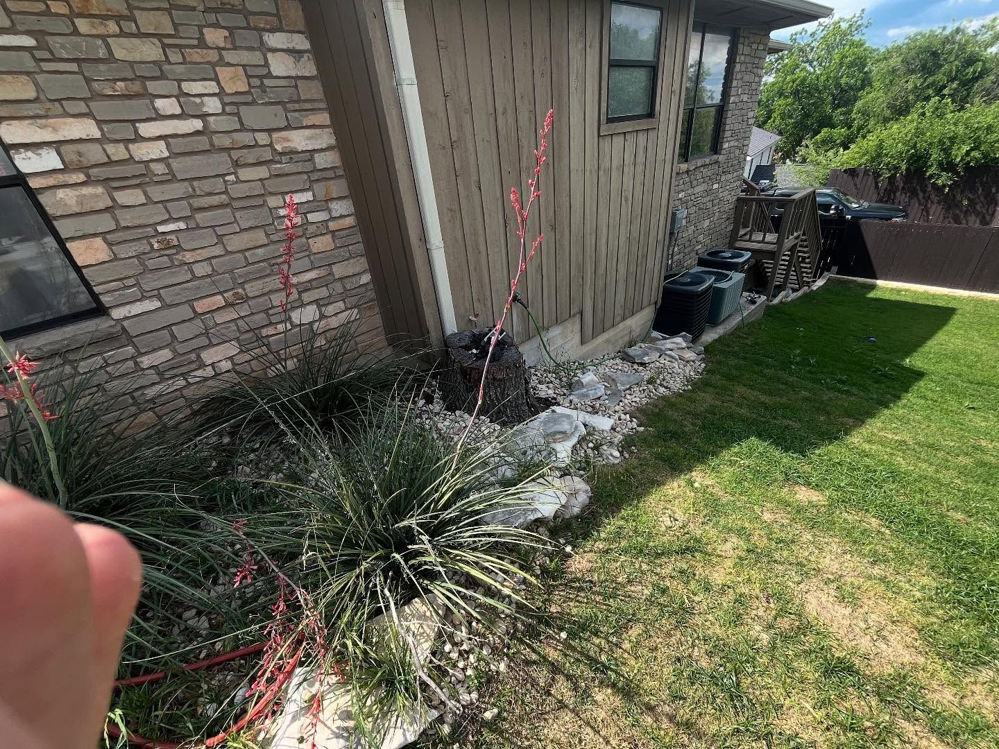 House exterior with stone and wood siding, rock border, and grass lawn.