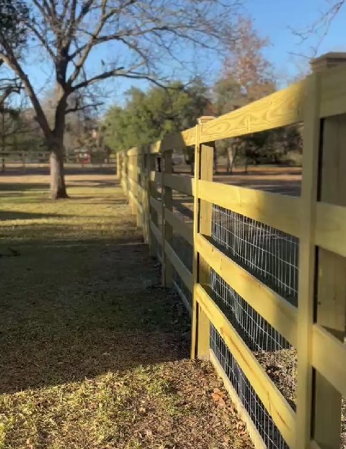 Red trailer with metal mesh sides and large metal box mounted on it, outdoors.