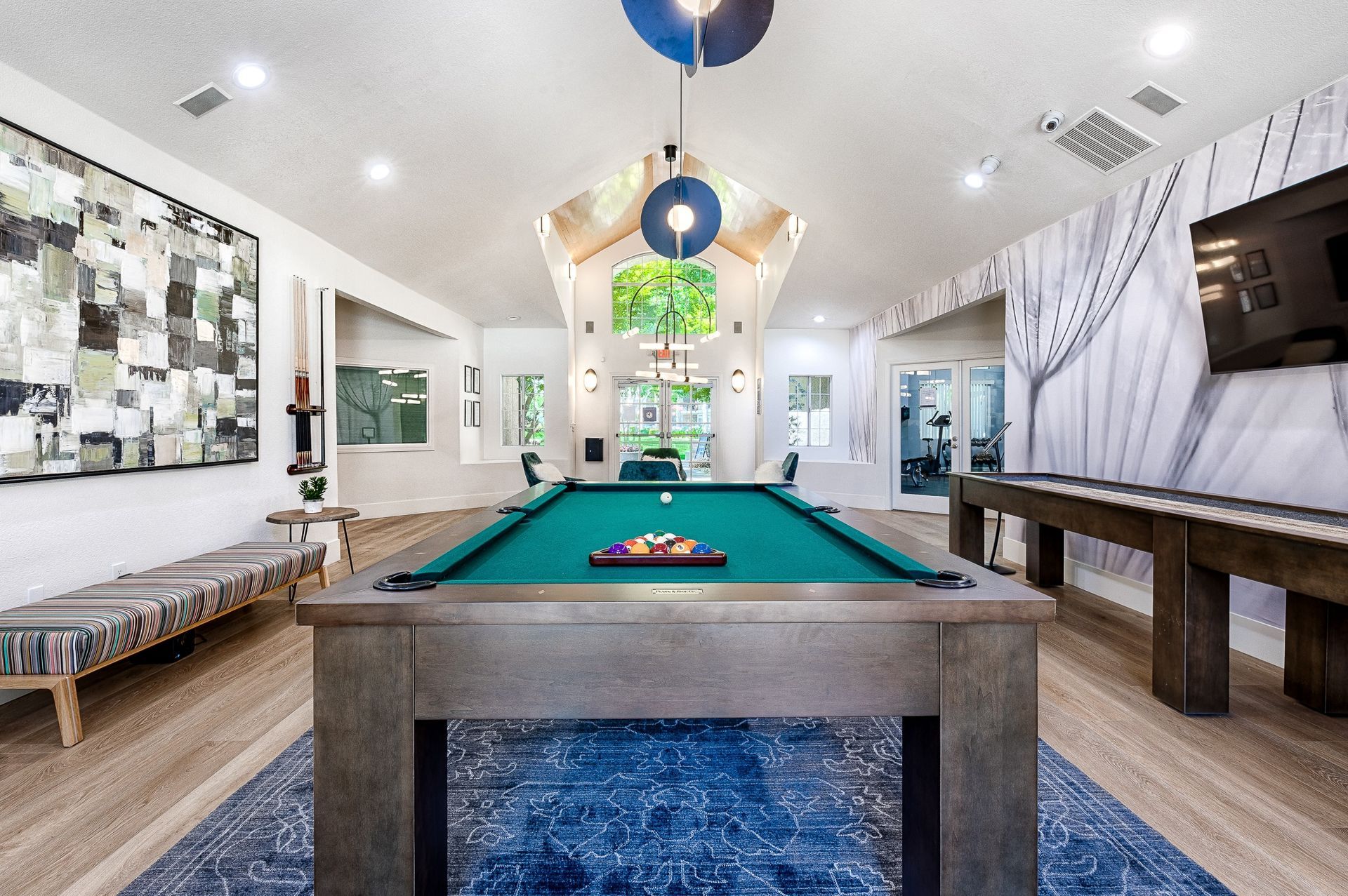 Interior community recreation room with pool table, bench seating, wall art, and a TV.