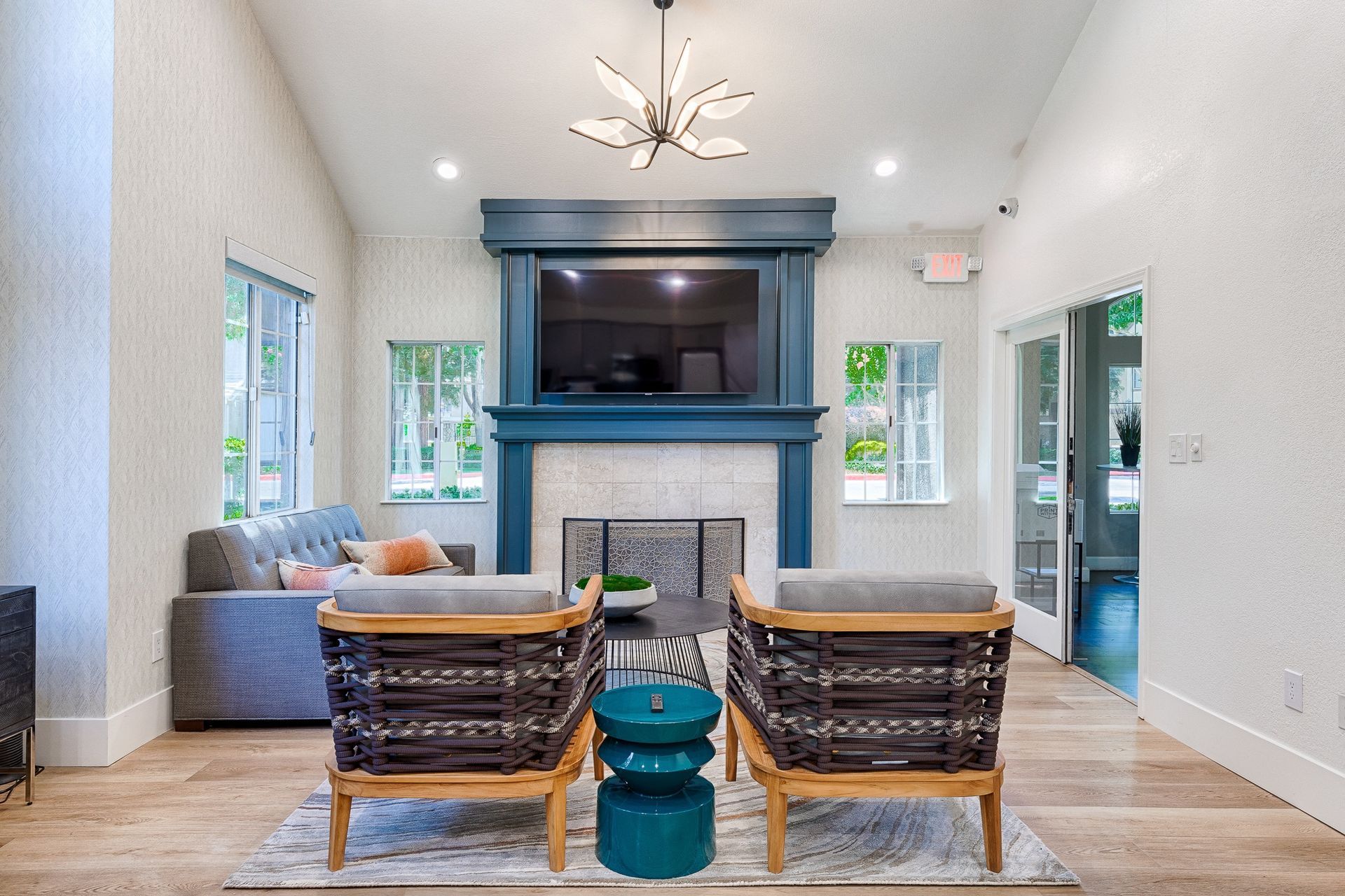 Living room in an apartment with a teal fireplace surround, modern seating, and a wall-mounted TV.