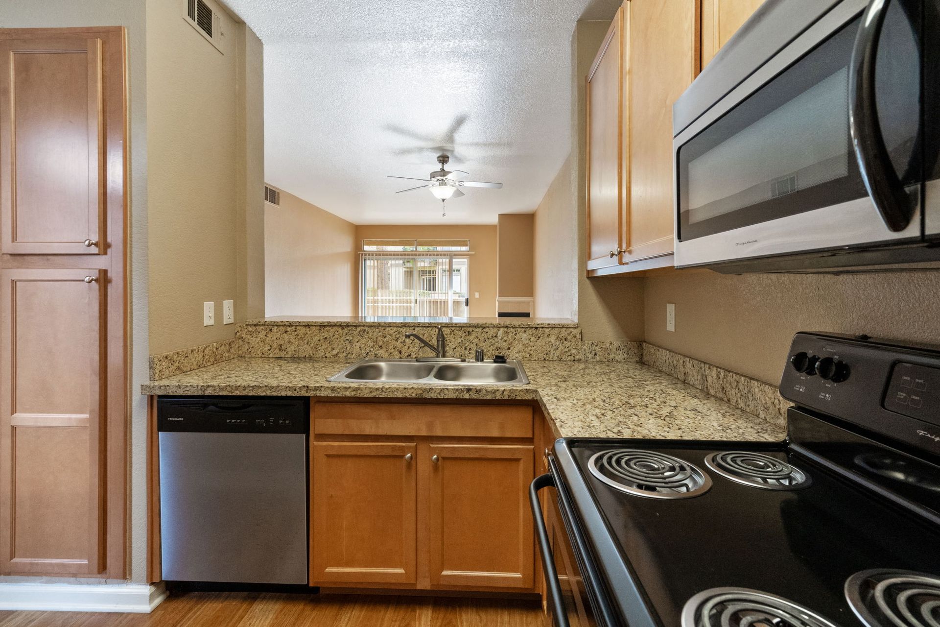 Kitchen with granite countertops, double sink, dishwasher, microwave, and stove in an apartment.