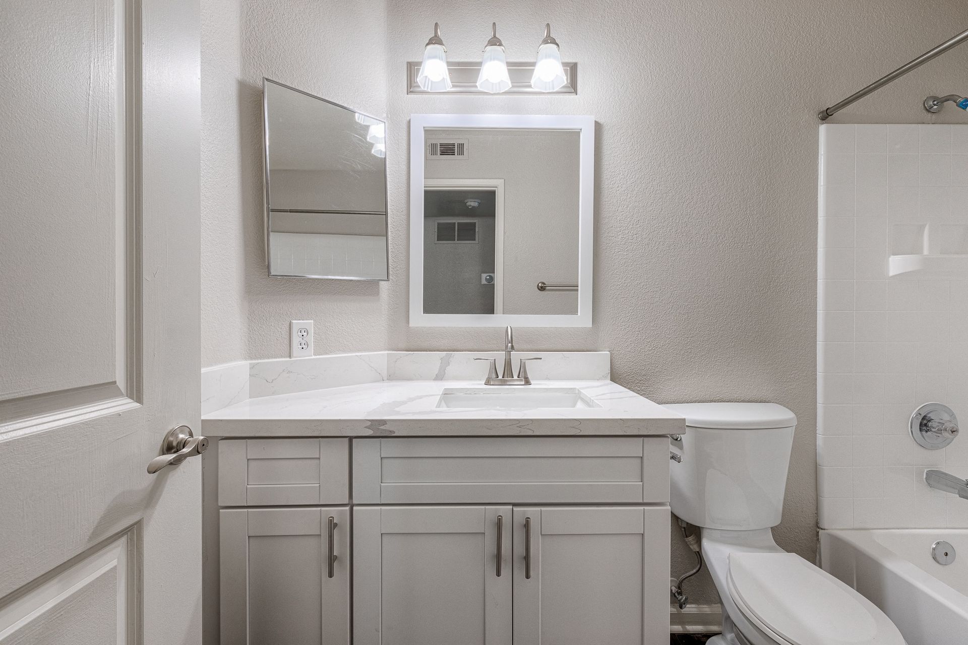 Bathroom vanity with sink, mirror, and toilet in a modern apartment.