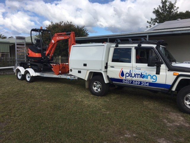 work ute towing excavator — Plumbing And Gas Services In Bundaberg, QLD