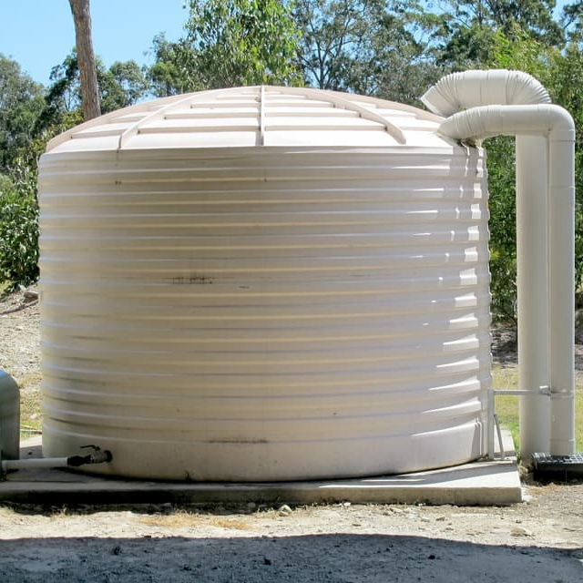 Large Rain Water Tank In Suburban Backyard — Plumbing And Gas Services In Bundaberg, QLD