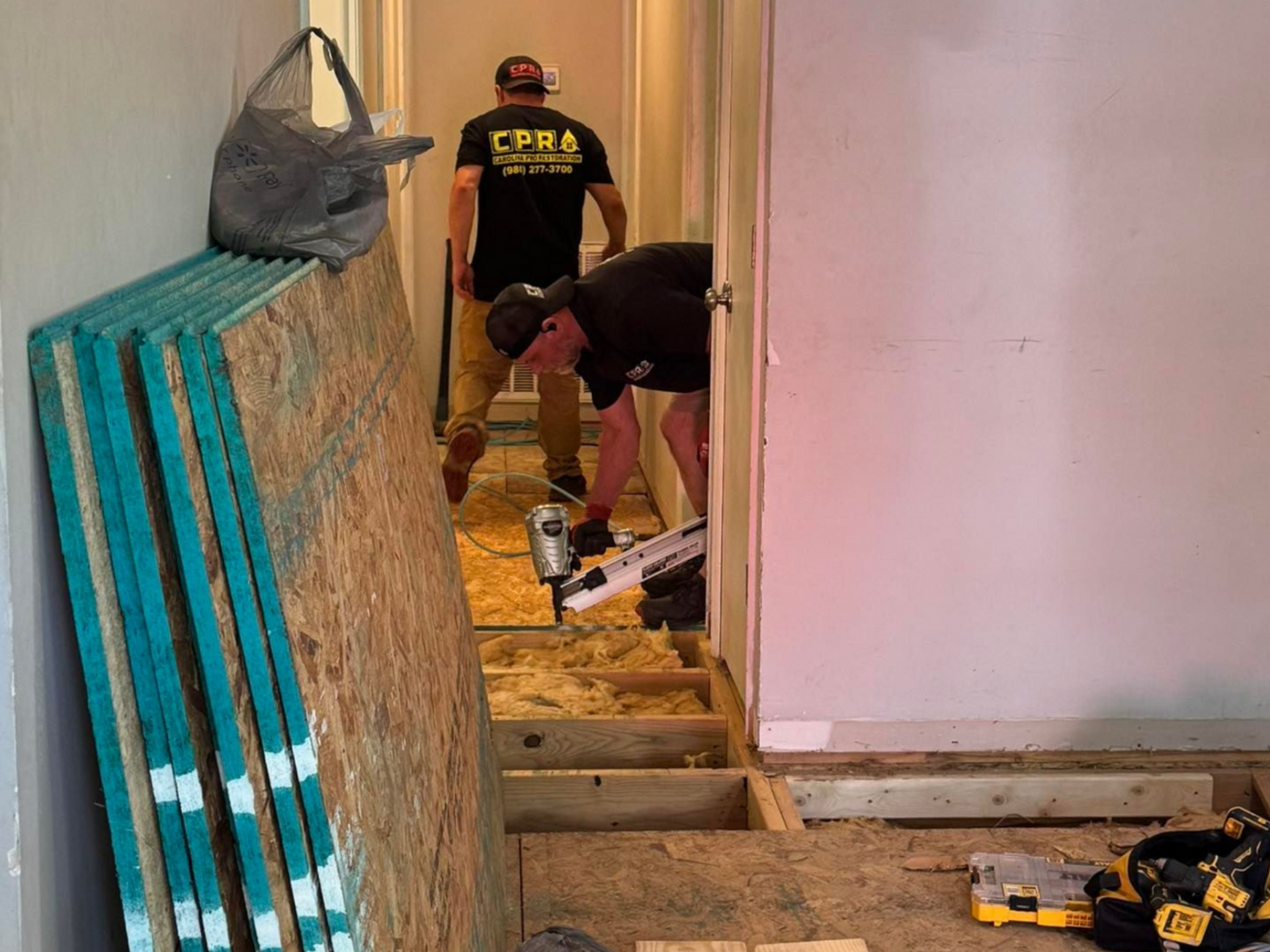 A man wearing a hard hat and gloves is using a device to measure the thickness of a wall.