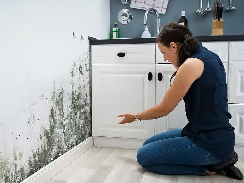 A man wearing a hard hat and gloves is using a device to measure the thickness of a wall.