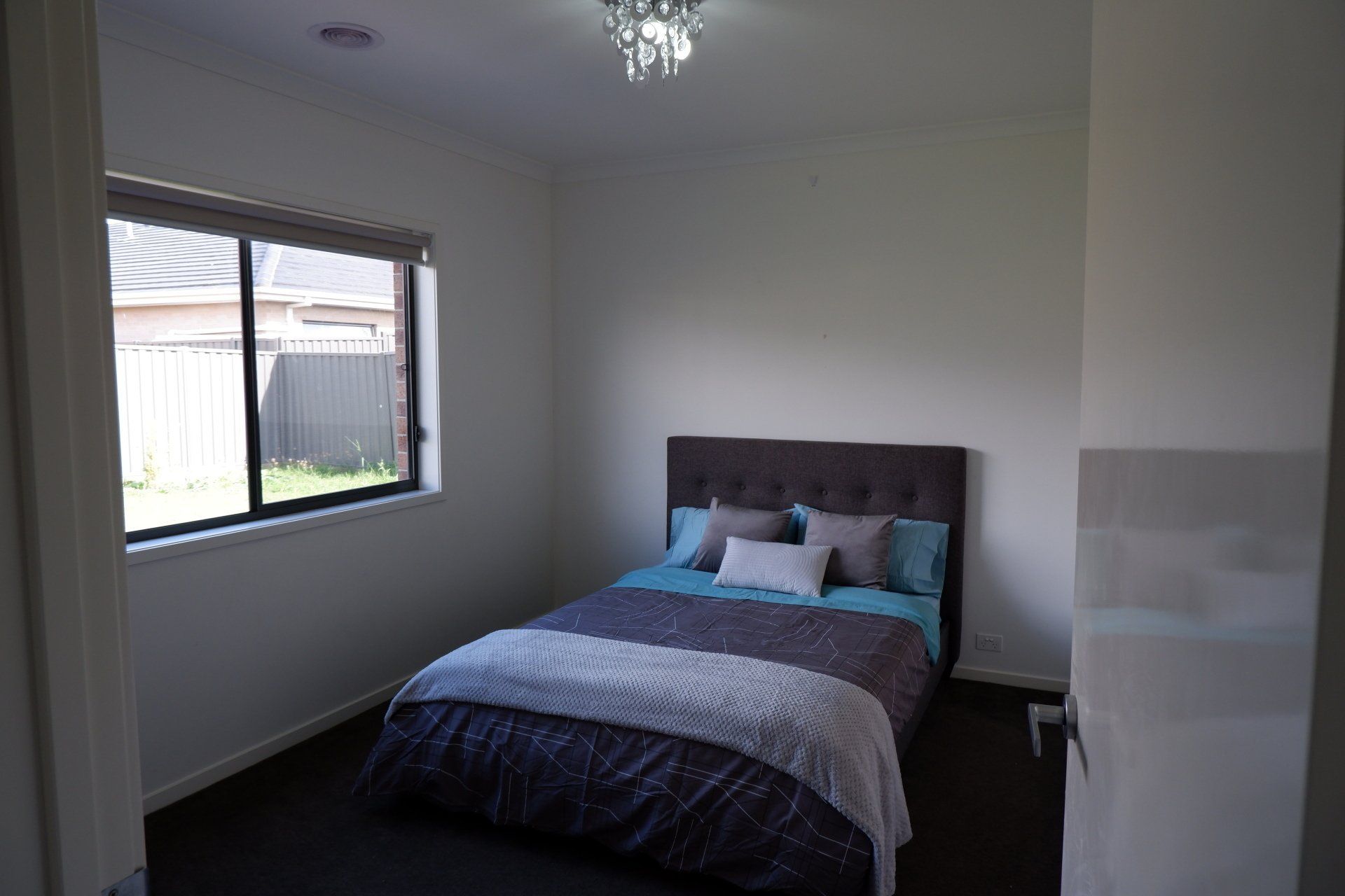 A bedroom with a bed , window and chandelier.