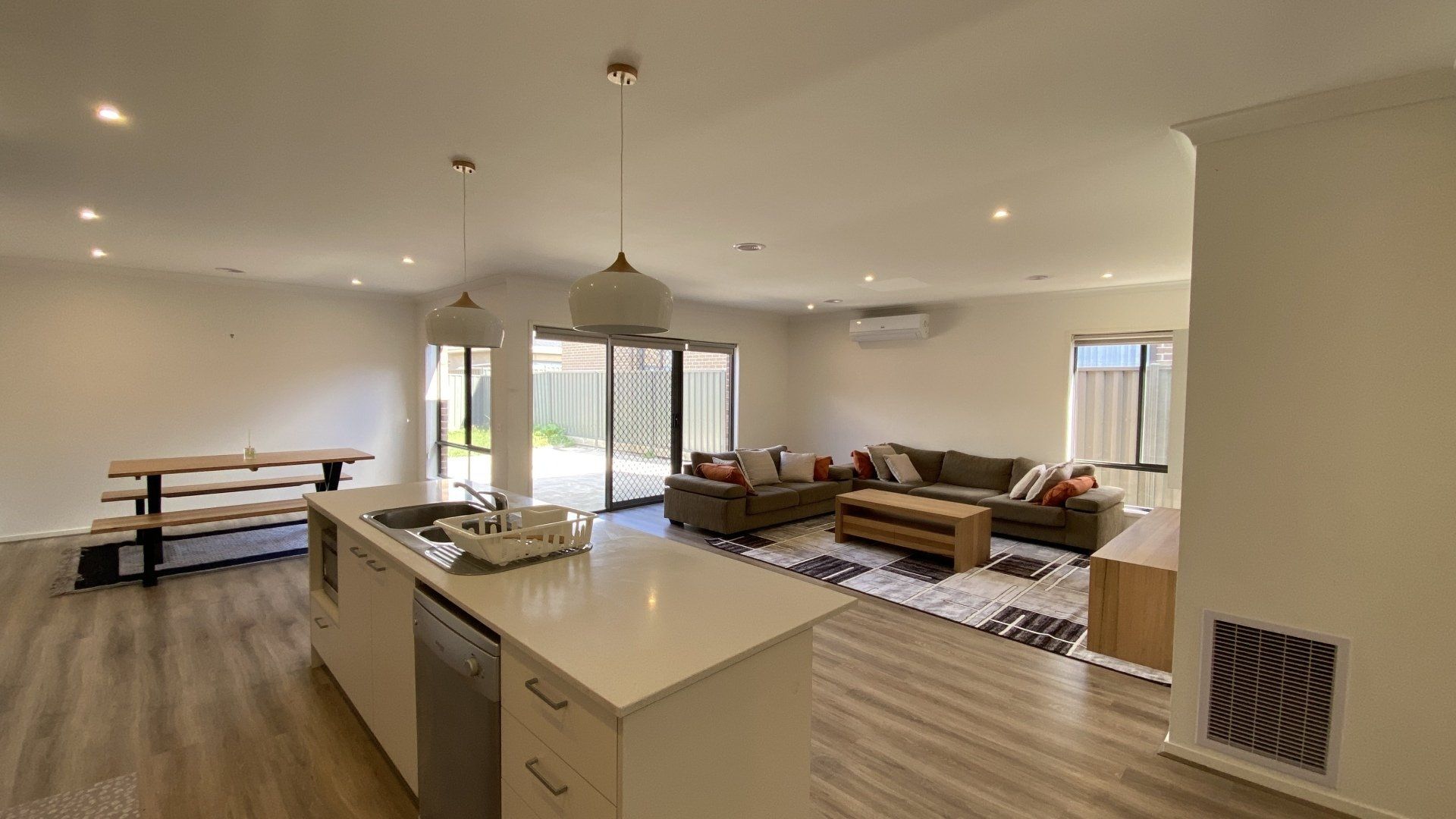 A kitchen and living room in a house with a large island in the middle of the room.