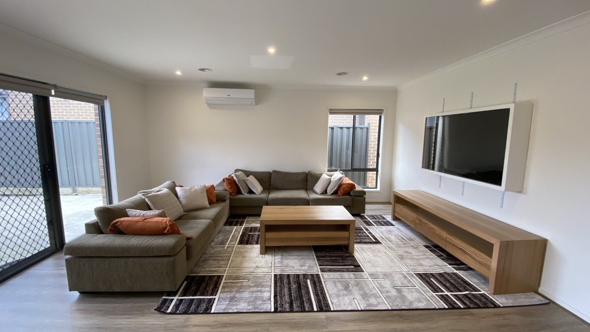 A living room with a large sectional couch , coffee table , and television.